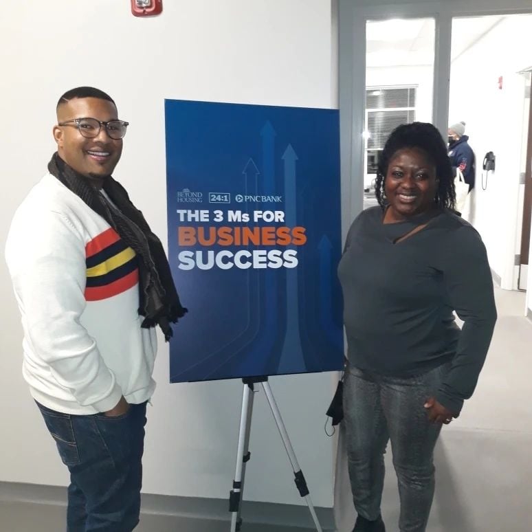 Two people beside a sign